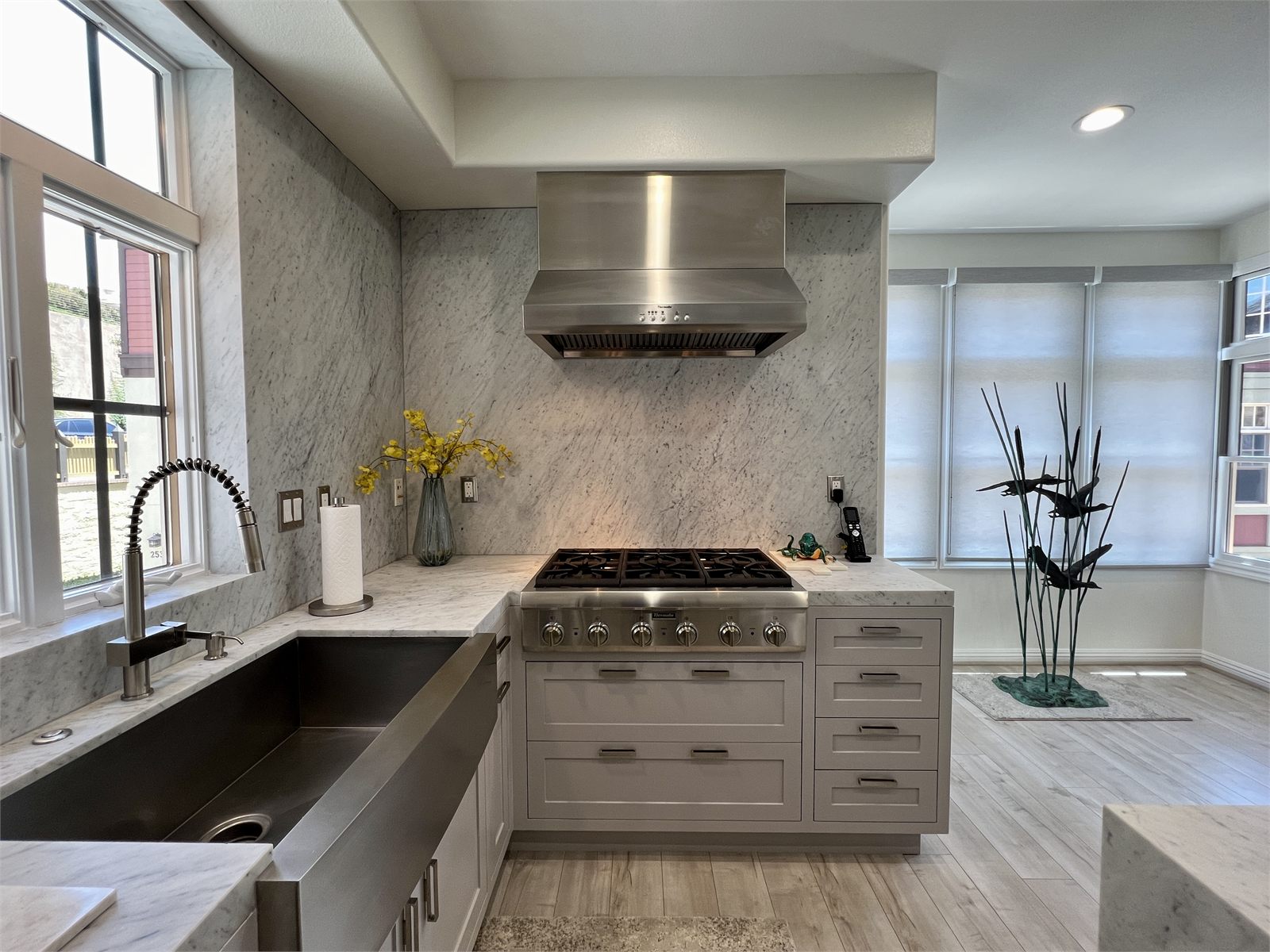 Kitchen range with a large stainless hood and black countertops