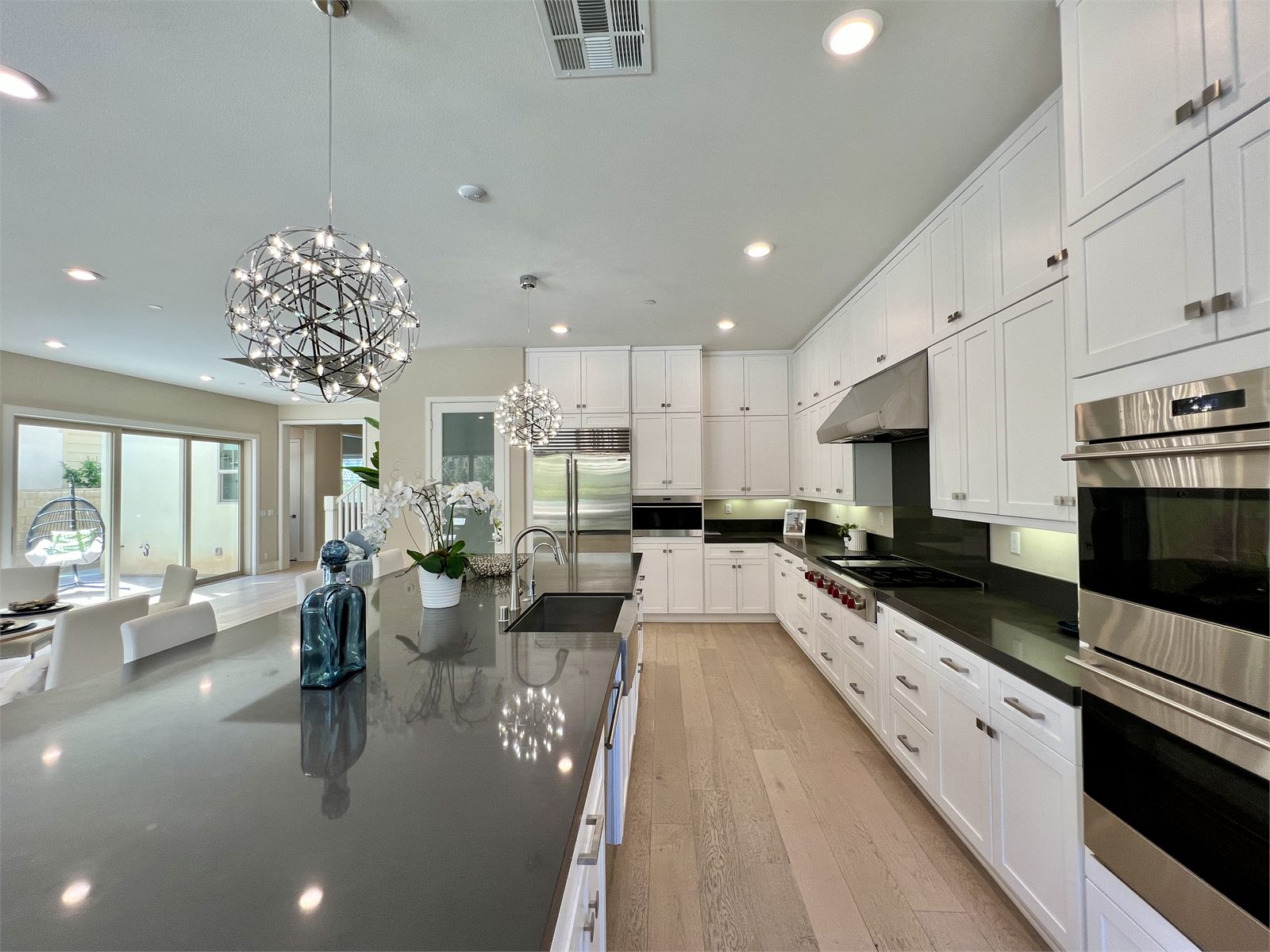 Finished kitchen with white cabinets, black countertops, a central island, and a stainless range hood